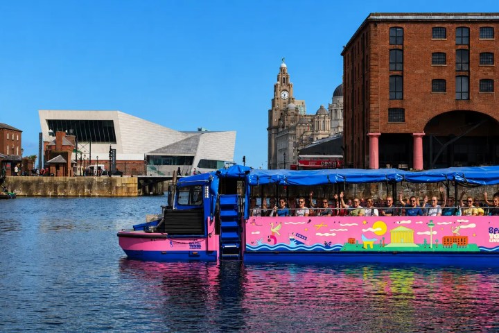 Colorful boat on water near brick buildings and modern architecture.