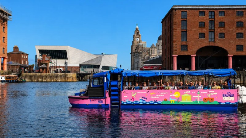 Colorful boat on water near brick buildings and modern architecture.